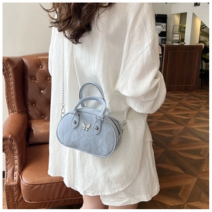 Close-up of light blue wrinkled texture handbag with a silver metal butterfly detail