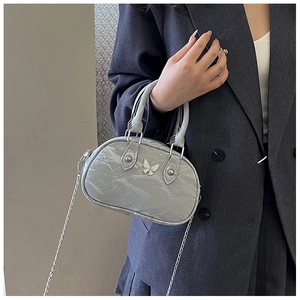 Detail of grey mini bowling bag featuring silver butterfly and chain strap on a model