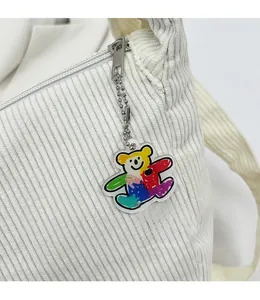 Detail of white corduroy fabric texture and a colorful graffiti bear acrylic keychain