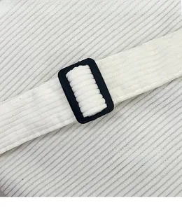 Detail of adjustable black buckle on white corduroy shoulder strap for modern handbags