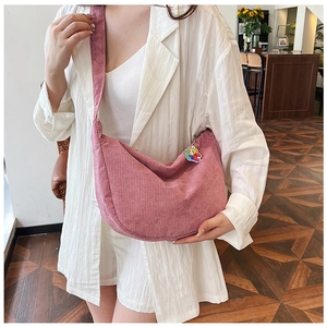 Pink corduroy crescent crossbody bag with cute rainbow bear charm shown on model