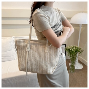 Detail view of woven straw tote bag with textured stripes and long faux leather shoulder strap