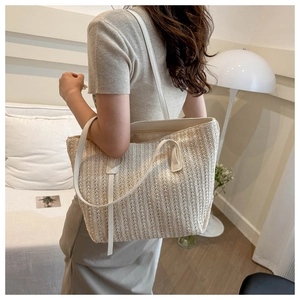 Rear view of model wearing large beige woven tote bag with white leather straps