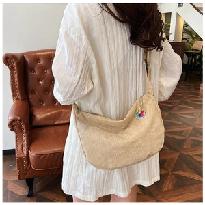Detail of beige corduroy crescent crossbody bag with cute rainbow bear pendant