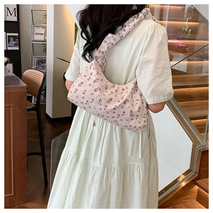 Detail einer floralen Canvas-Tasche mit Scrunchie-Schultergurt an Frau im grünen Kleid