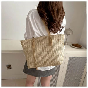 Macro detail of the woven straw texture and premium brown leather straps on a tote bag