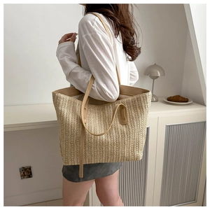 Detailed close-up of straw tote bag showing beige vertical weave texture and brown leather strap