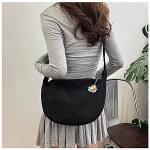 Detail of black corduroy crescent crossbody bag with a colorful rainbow bear charm
