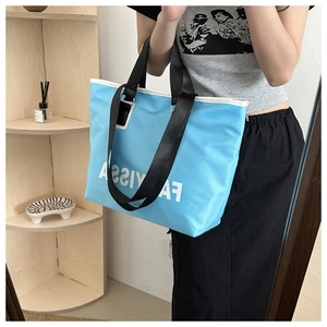 Detail of light blue Oxford tote bag with black handles and white Fayissa lettering