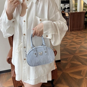 Light blue bowling bag with butterfly ornament and silver chain on a wooden floor