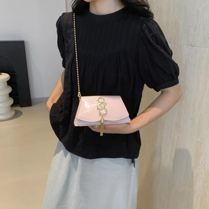 Pink patent leather crossbody bag with gold chain and fringe detail on model
