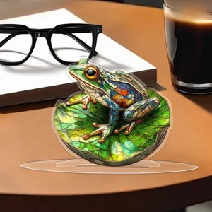 Flat 2D acrylic frog ornament in stained glass style on a cozy wooden desk setting