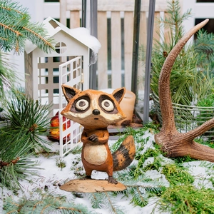 Detailed view of a cartoon raccoon garden stake with hand-carved textures in a snowy setting
