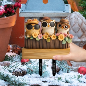 Detailed view of hand holding cute resin owl garden stake stakes in snowy outdoor scene