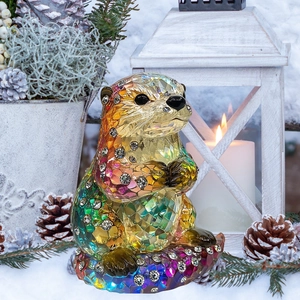 Faceted iridescent sea otter ornament with crystal accents in a cozy winter scene