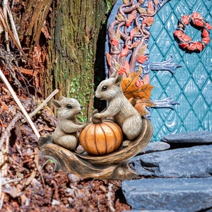 Macro detail of resin squirrel and pumpkin figurines in a fairy garden landscape