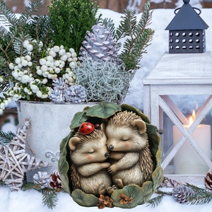 Detailed view of hedgehog garden ornament nestled in a leaf among winter snow and lantern