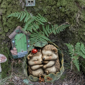 Close-up of sleeping hedgehogs in a leaf nest with a ladybug and fairy garden decor