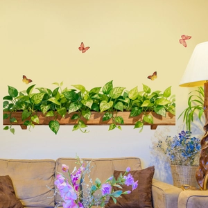 Detail of green potted plant wall stickers and colorful butterflies above a cozy sofa