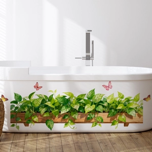 Detail of green pothos plant wall stickers with colorful butterflies on a white bathtub