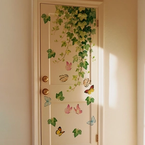 Detail of green vine and colorful butterfly wall stickers applied on white wood door