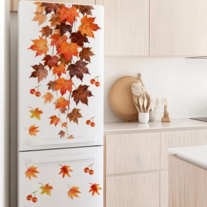 Detail of autumn maple leaves and red berry stickers on a white refrigerator surface