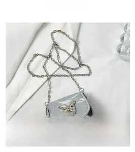 Macro detail of silver butterfly metal buckle and shiny leather texture on mini saddle bag