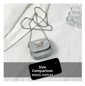 Size comparison of silver mini saddle bag with butterfly chain and smartphone