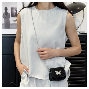 Detail of mini black saddle bag with silver butterfly metal clasp and chain strap
