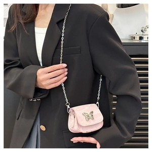 Detail of pink mini saddle bag with silver butterfly chain shown on black blazer