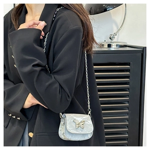 Detail of light blue mini saddle bag with silver butterfly buckle and chain strap