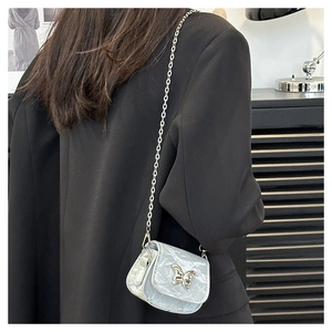 Detail of mini marble saddle bag with silver butterfly charm and metal chain strap