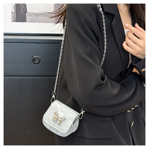Chic mini silver saddle bag with gold butterfly clasp and chain strap on a model