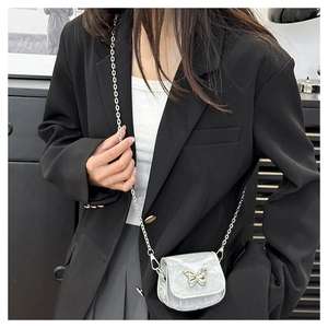 Close-up of mini saddle bag with silver butterfly buckle and chain strap on a black blazer