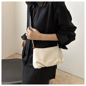 Detalle del bolso de nube plisado beige con cuenta de ámbar en la correa de hombro