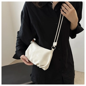 Primer plano del bolso nube fruncido blanco con correa sobre modelo en camisa negra