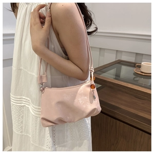 Primer plano de bolso nube rosa claro con cuenta de ámbar y textura plisada en asa