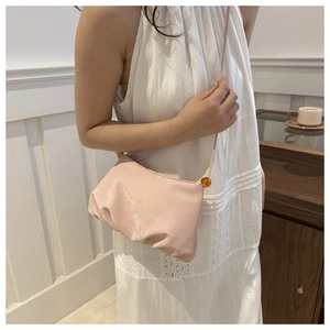 Detalle de bolso nube plisado rosa con cuenta de ámbar y correa de hombro delgada