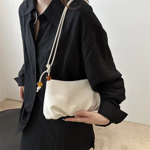 Bolso nube blanco plisado con cuentas de ámbar mostrado en modelo con camisa negra chic