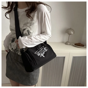 Détail d'un sac bandoulière noir avec logo blanc et sangle ajustable porté par un mannequin