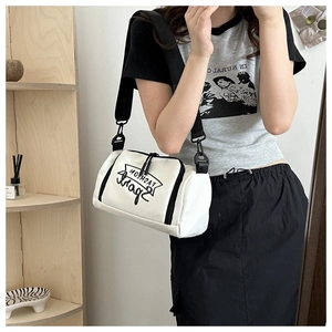 Détail d'un sac bandoulière cylindrique blanc en toile avec texte Fashion Sport et sangle