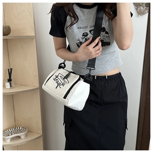 Détail d'un sac bandoulière blanc cylindrique avec logo FASHION et sangle noire