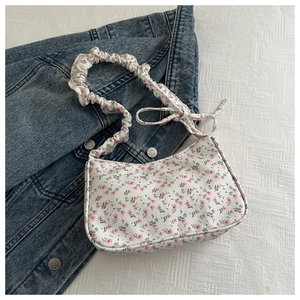 Close-up of white floral underarm bag with pink tulips and ruffled shoulder strap bow