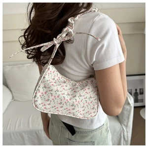 Detailed view of floral shoulder bag featuring scrunchie strap and pink bow decorations