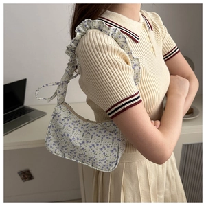 Floral print hobo bag with ruffled shoulder strap shown in a casual indoor setting