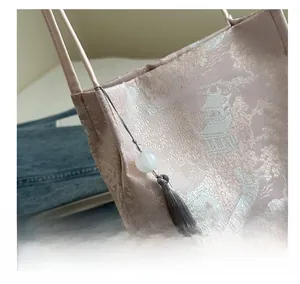 Detailed close-up of pink brocade embroidery bag with grey tassel and white bead charm
