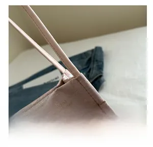 Detail of pink embroidered silk tote bag showing premium stitching and leather handle