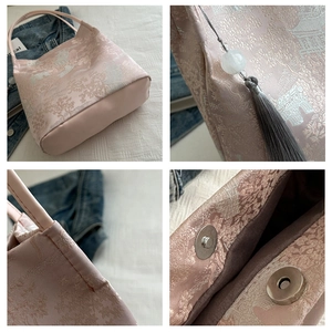 Detail view of pink Chinese brocade tote featuring jacquard pattern and tassel charm