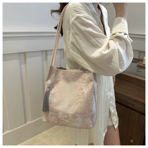 Detail of pink brocade tote with jacquard tree patterns and a decorative tassel pendant