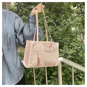 Detail of floral embroidery on light pink satin tote bag with silk tassel accent